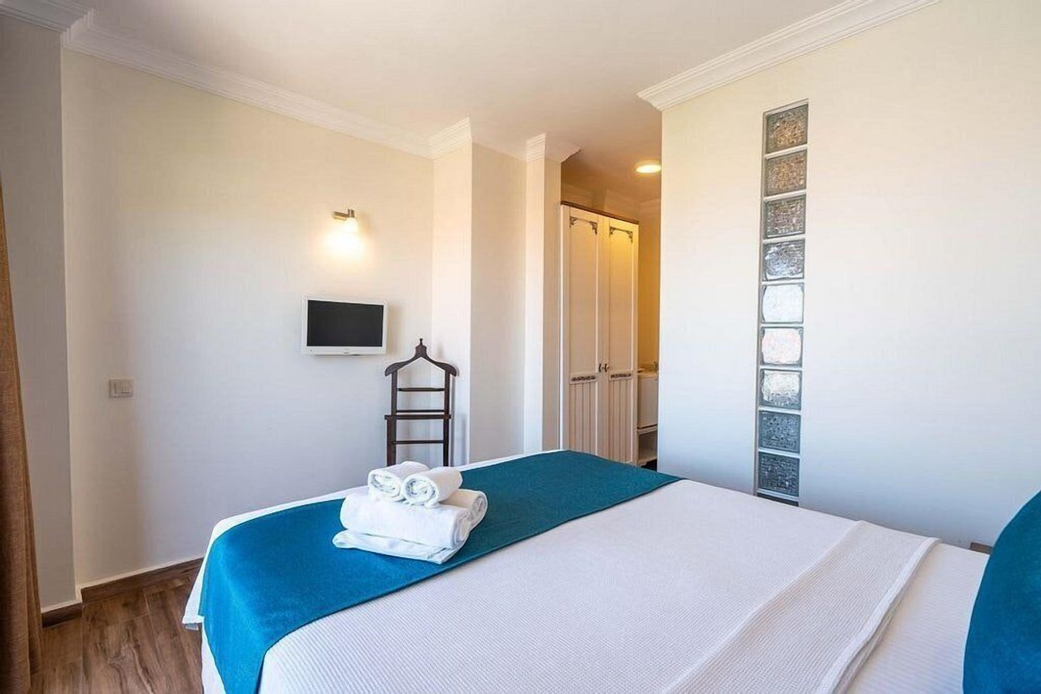 Ein Hotelzimmer mit Bett, Fernseher, Kleiderschrank und Dusche.