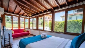 A bedroom with a bed, a red sofa, and large windows. - Cunda Giritlioğlu Otel (Ayvalik)
