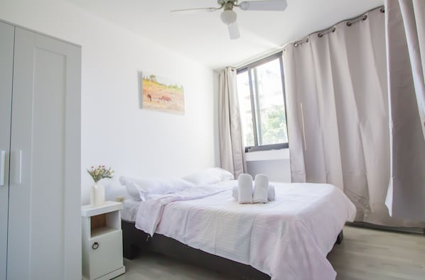A bedroom with a bed, a nightstand, a wardrobe, and a window with curtains. - Apartment - Tel Aviv (Tel Aviv)