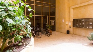 Una entrada de edificio con un gran escaparate de vidrio, una fila de bicicletas y un buzón en la pared.
