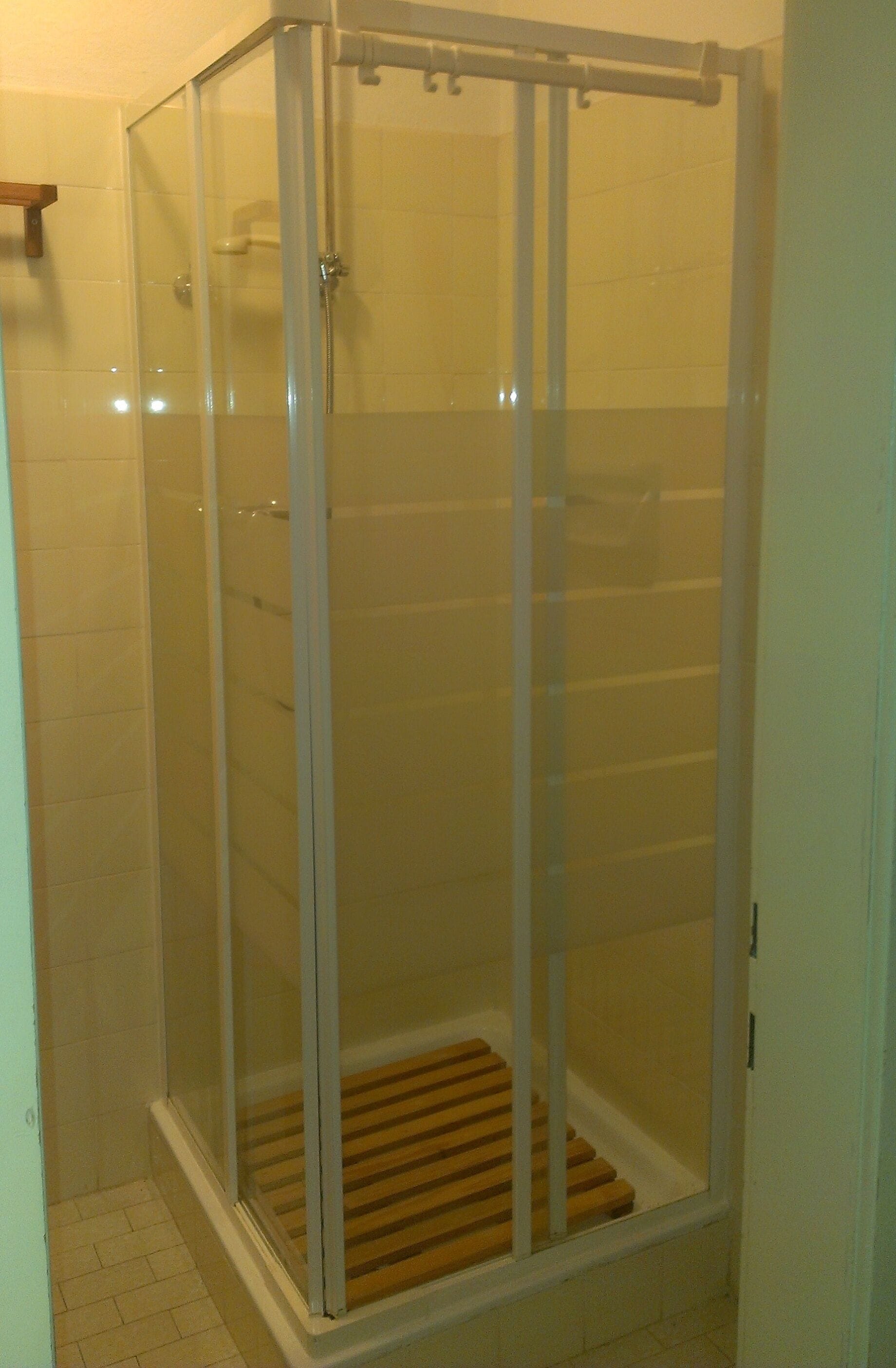 Un box de ducha con paredes de vidrio y un banco de madera.
