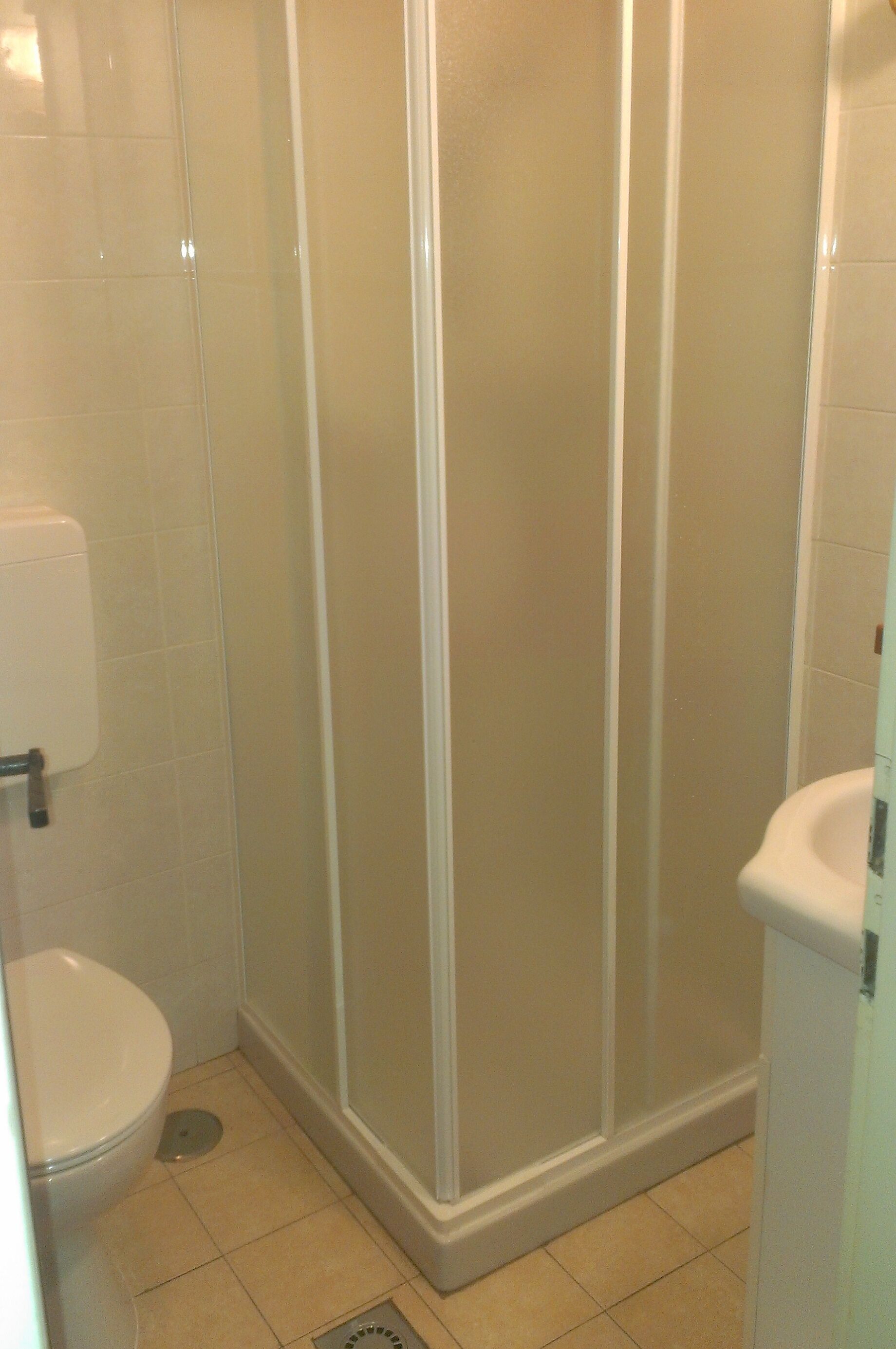 Un baño con inodoro, cabina de ducha y lavamanos.