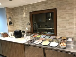Un buffet proposant une variété de plats et un distributeur de miel.