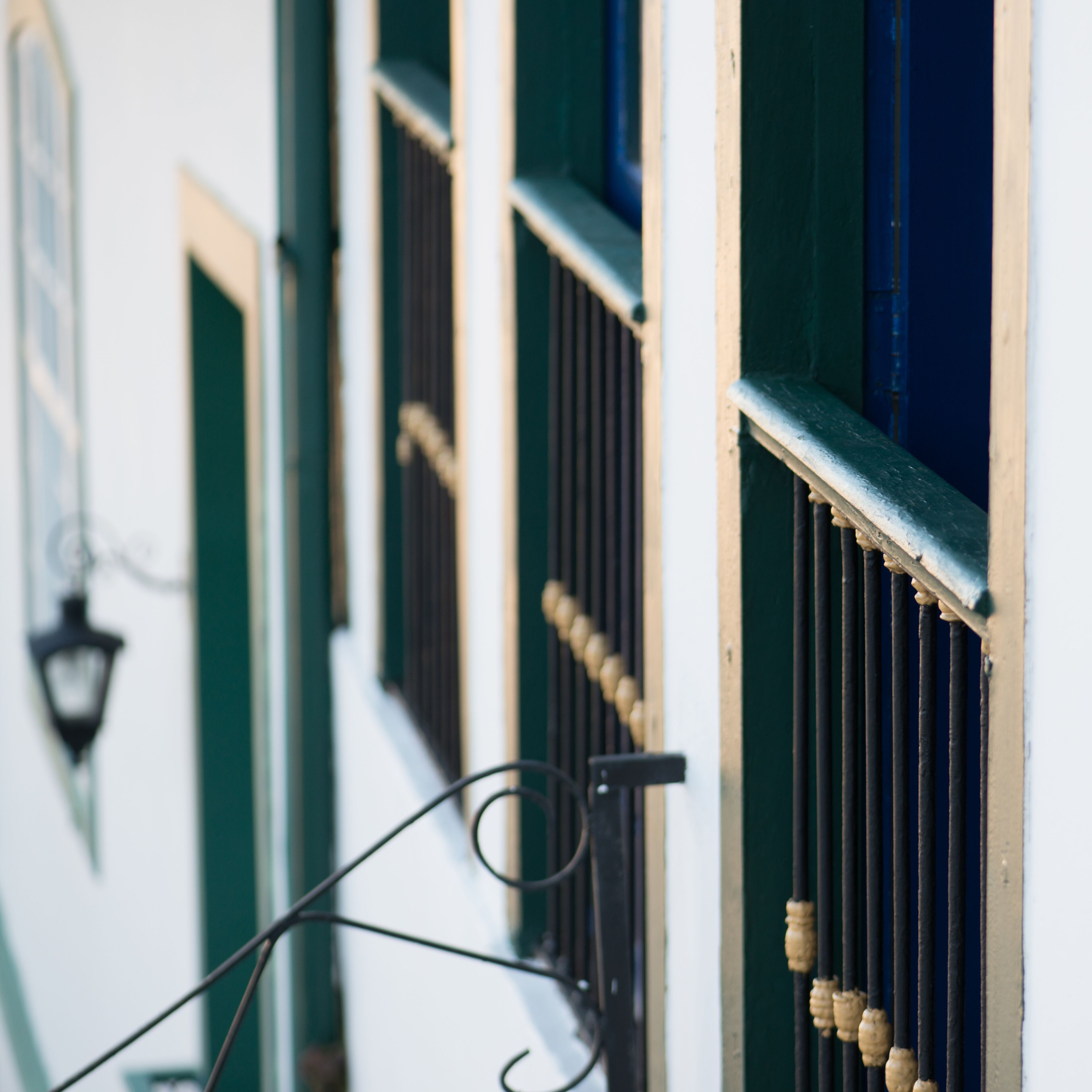 A close-up of a building facade with green shutters and a metal gate.