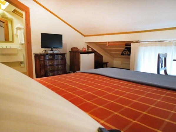 A bedroom with a bed, dresser, television, and a small refrigerator. - Pousada do Douro (Ouro Preto)