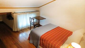 A bedroom with a bed, a desk, and a chair.