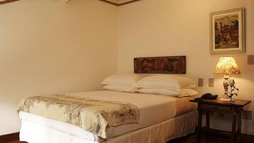 A neatly made bed with a floral bedspread, a bedside table with a lamp, and a painting on the wall.