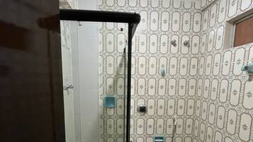 A bathroom with patterned tiles, a toilet, a shower area, and a door.