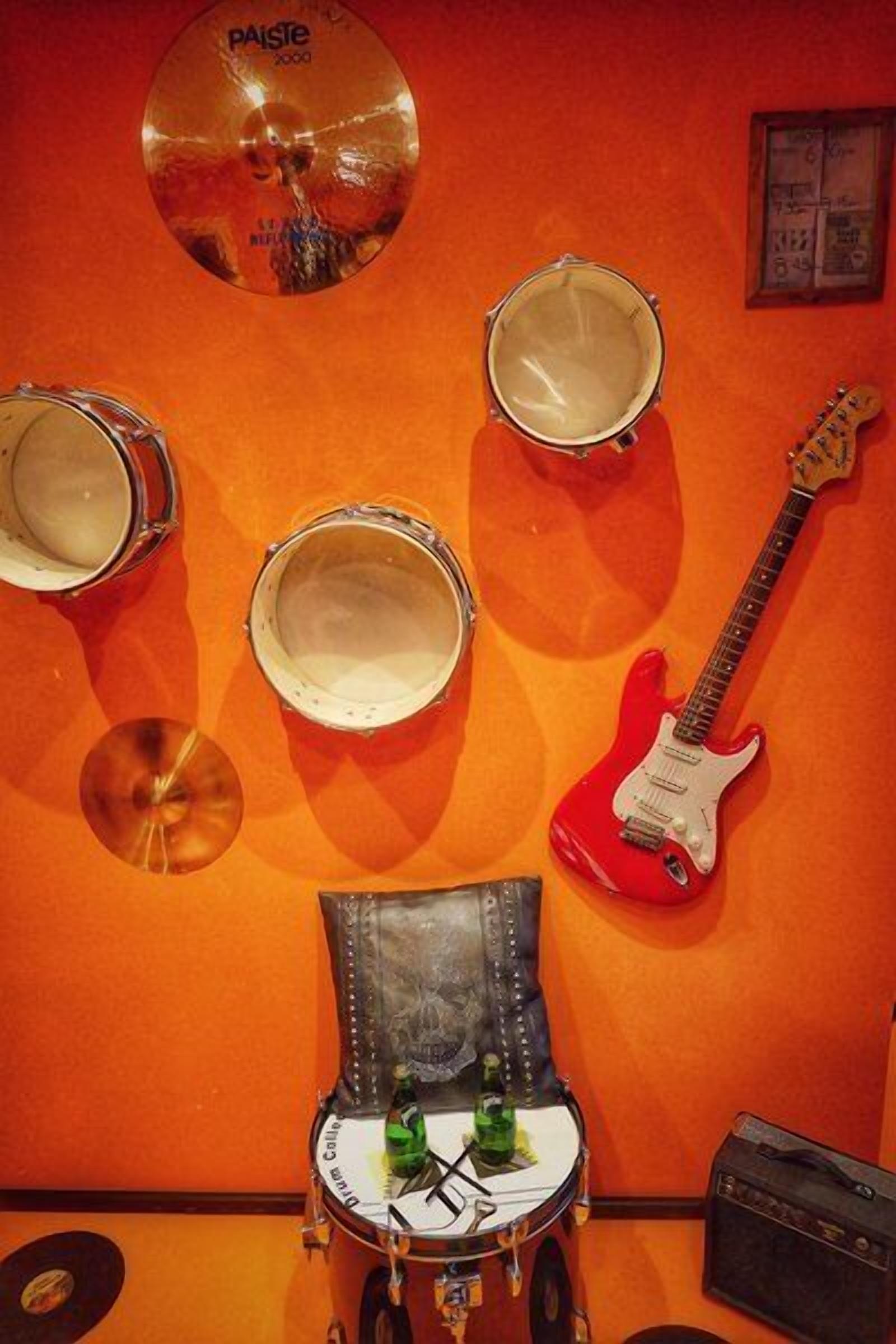 A room with a drum set, a red electric guitar, and a vintage radio.