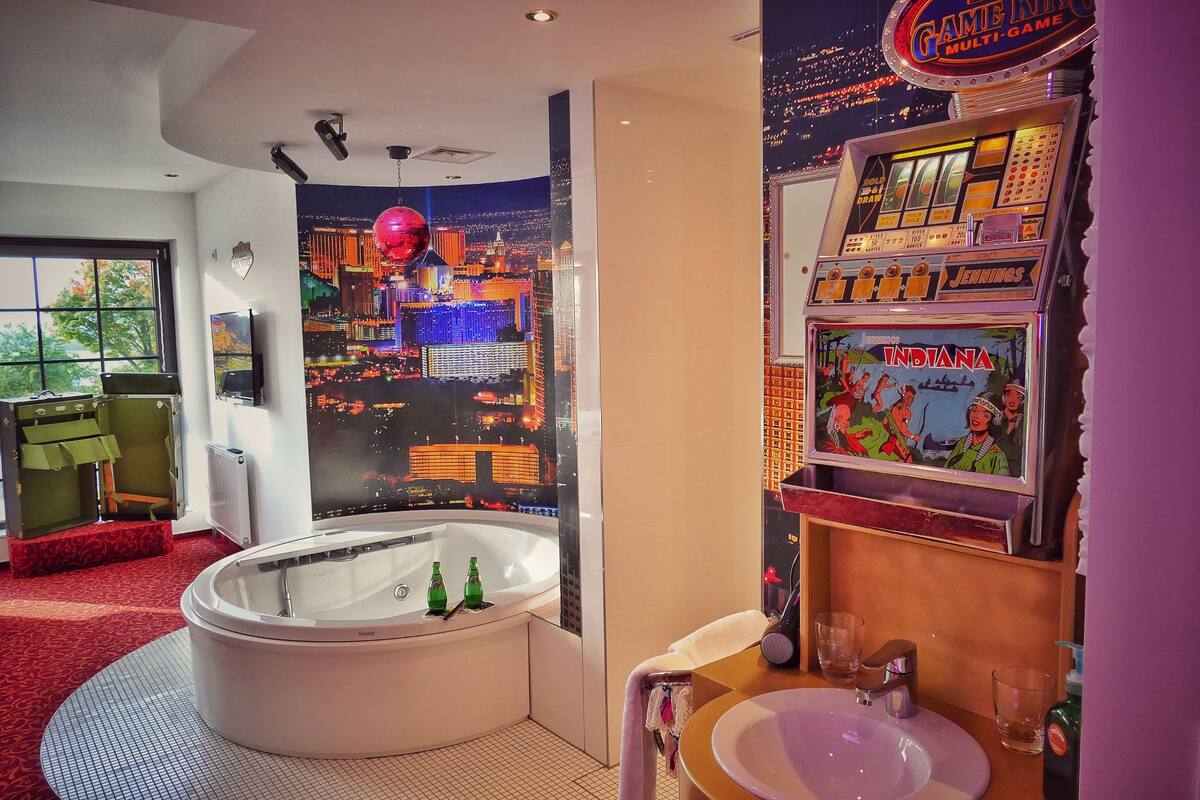 A luxurious bathroom with a large bathtub, a vanity with a sink, and a slot machine.