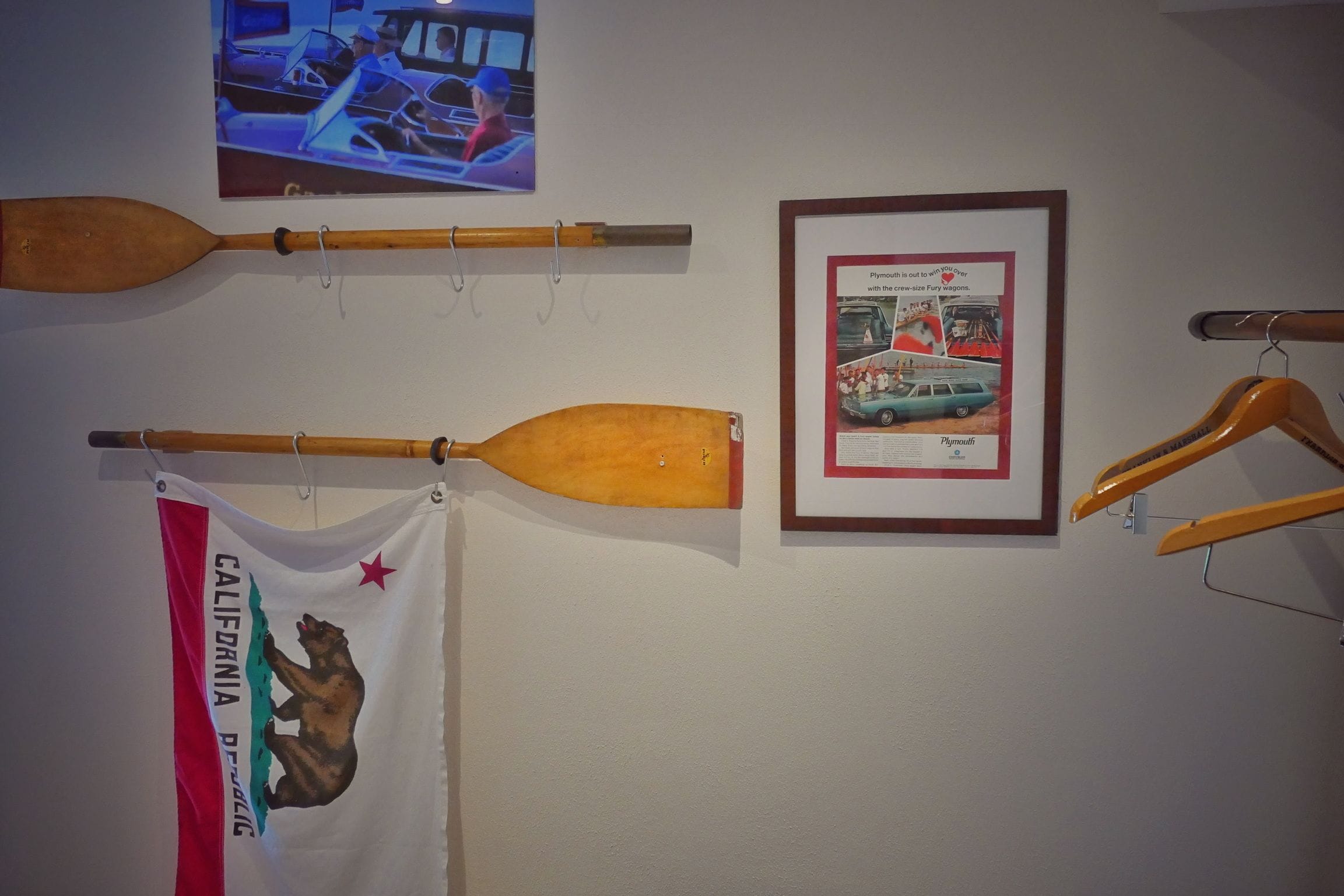 Eine Wand mit diversen Gegenständen, darunter ein Holzschläger, ein gerahmtes Werbeplakat und eine Flagge.