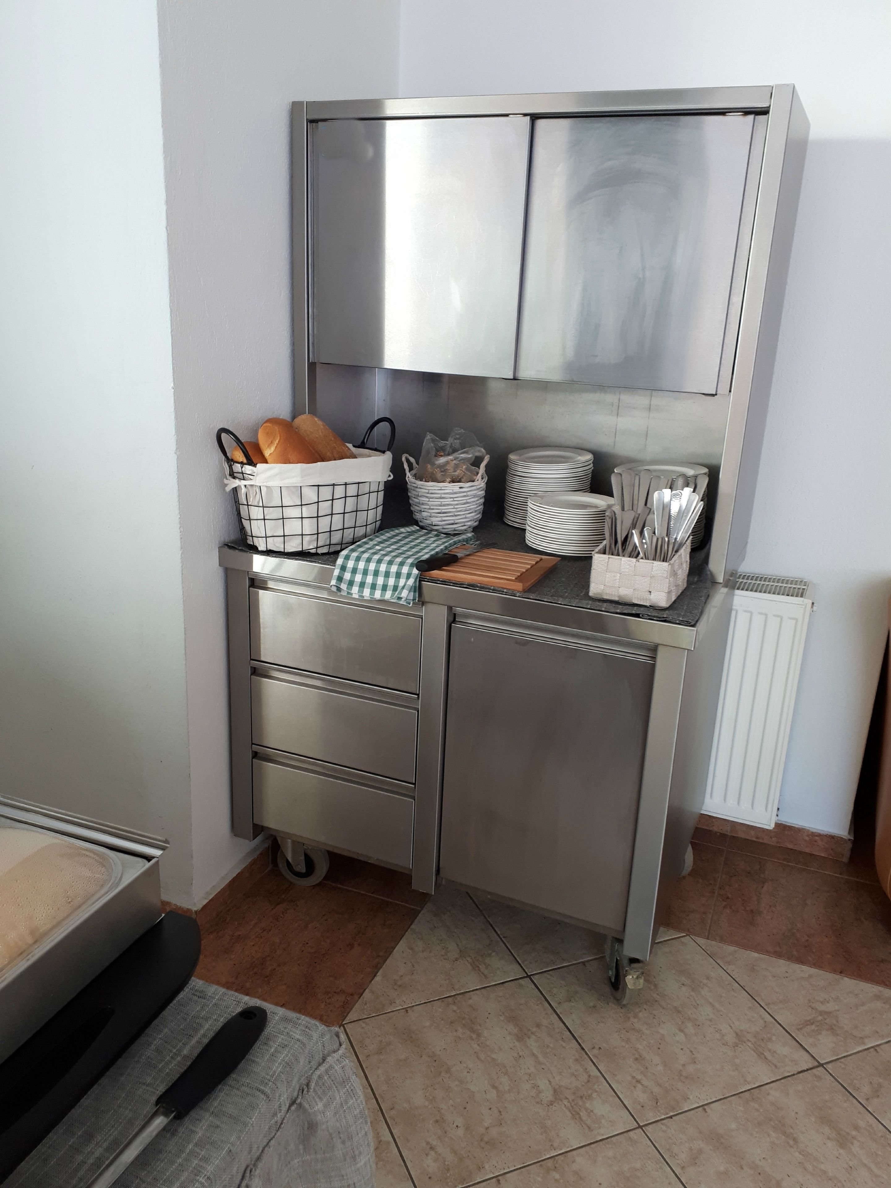 A stainless steel kitchen with a built-in refrigerator, a sink, and a countertop with various kitchen items.