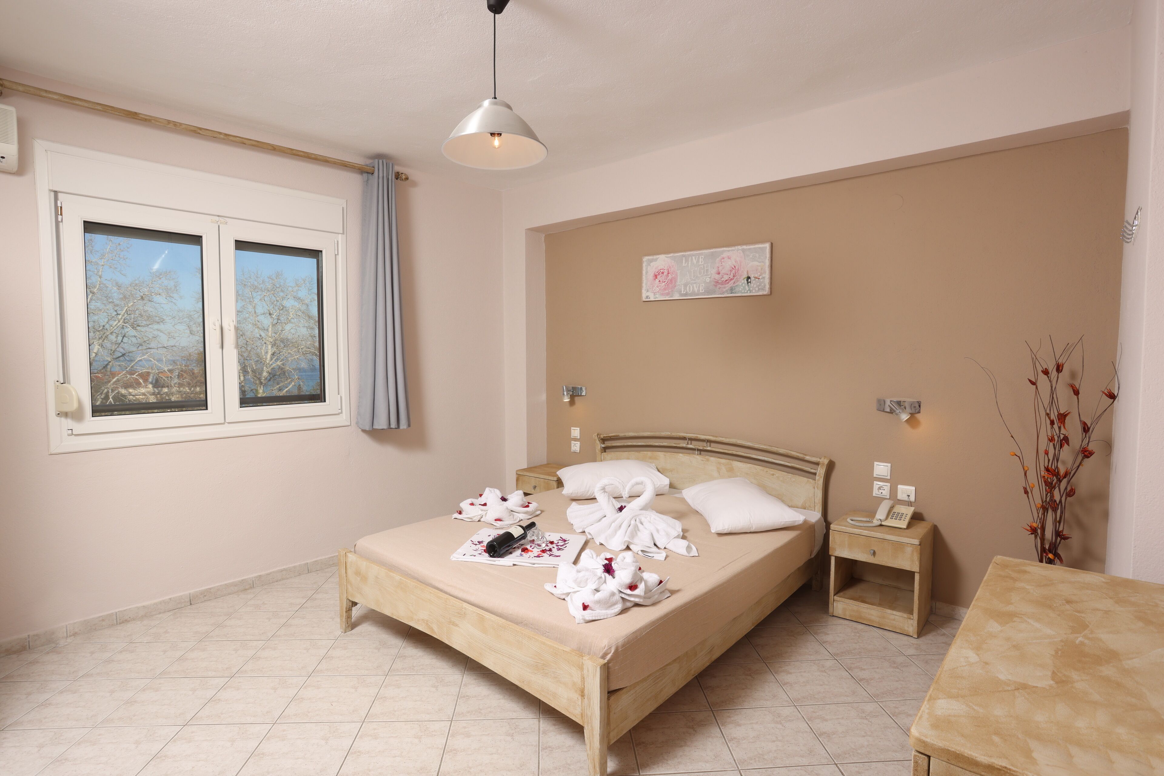 A bedroom with a bed, bedside table, nightstand, and a window with curtains.
