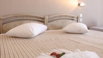 A neatly made bed with striped bedding, two pillows, and a folded towel with a flower.