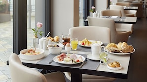 A breakfast setting with a variety of dishes, including eggs, toast, and pastries, on a table with a view of the outdoors. - LEGERE HOTEL Bielefeld (Bielefeld)
