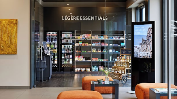 A modern retail space with shelves stocked with various products, a digital display, and seating areas. - LEGERE HOTEL Bielefeld (Bielefeld)