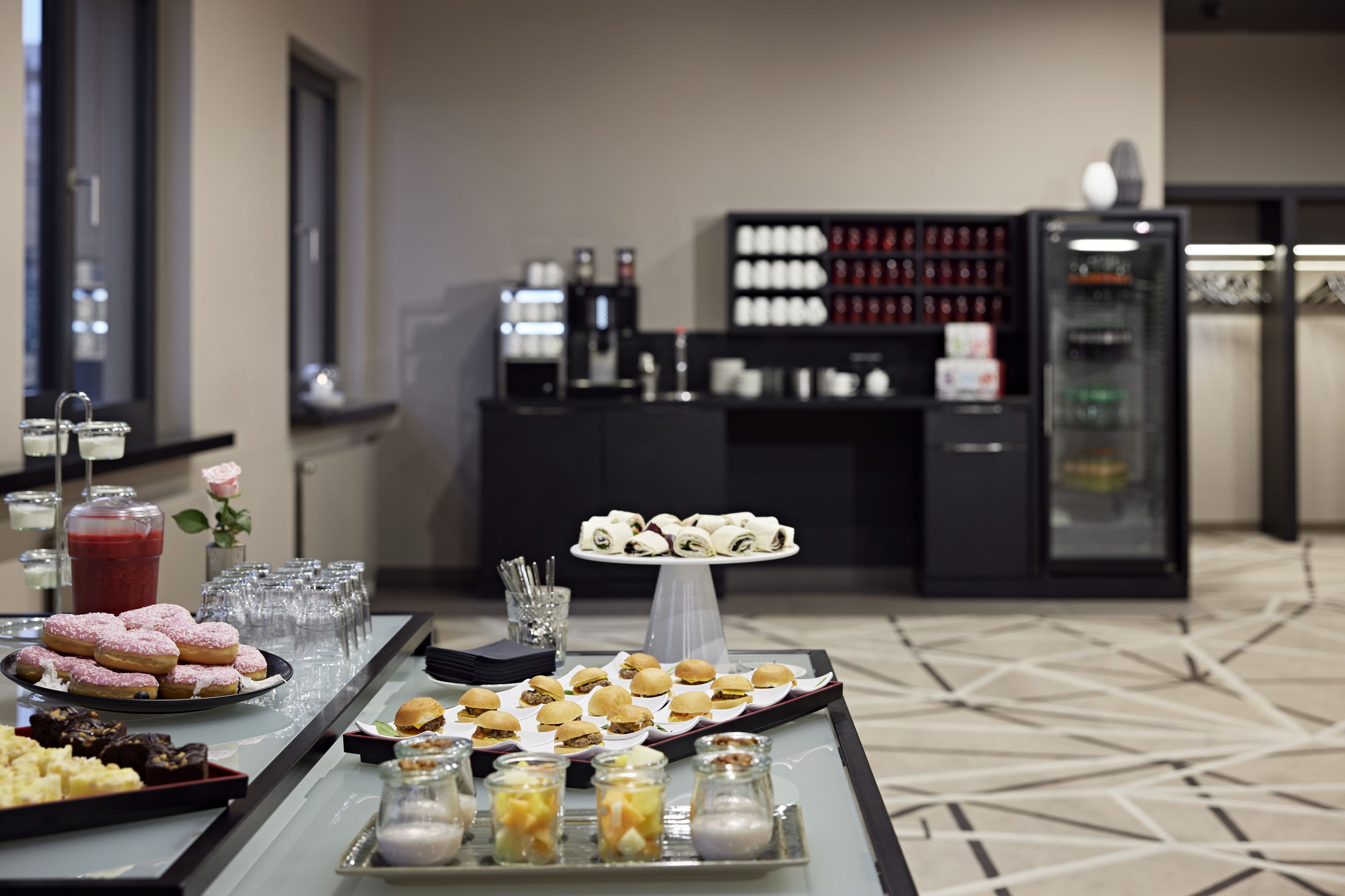 A buffet table with various food items and a beverage station in a hotel setting.