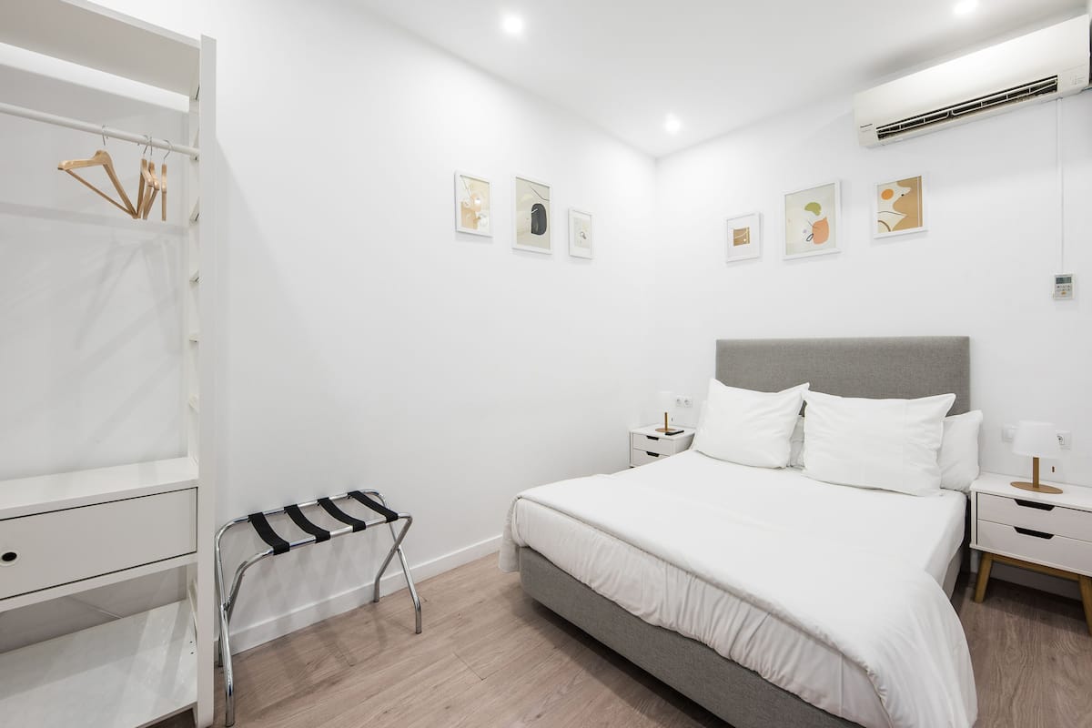 A modern bedroom with a bed, bedside tables, a wardrobe, and artwork on the wall.