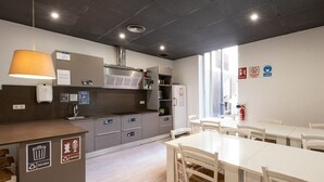 Una cocina moderna con una isla central, electrodomésticos integrados y un comedor con sillas blancas y una mesa.