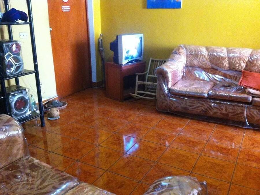 Un soggiorno con un divano, una televisione e uno scaffale con diversi oggetti.