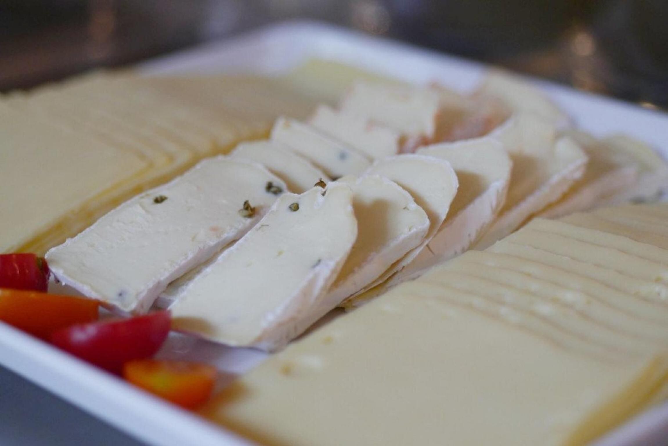 Une assiette de fromage blanc coupé en tranches, garnie d’herbes et accompagnée de quelques poivrons rouges et jaunes.