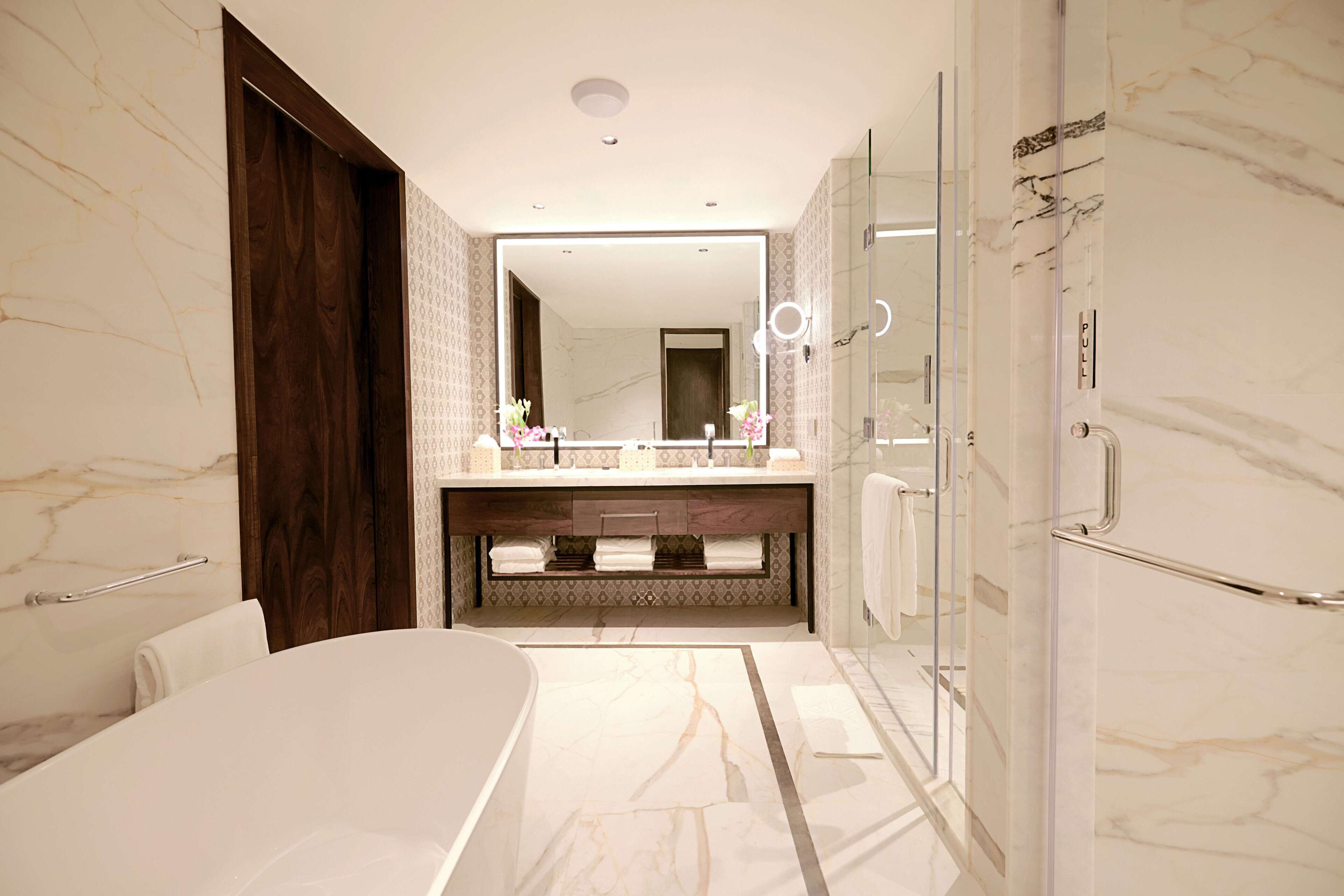 Un baño moderno con un espejo grande, una bañera y un box de ducha de vidrio.