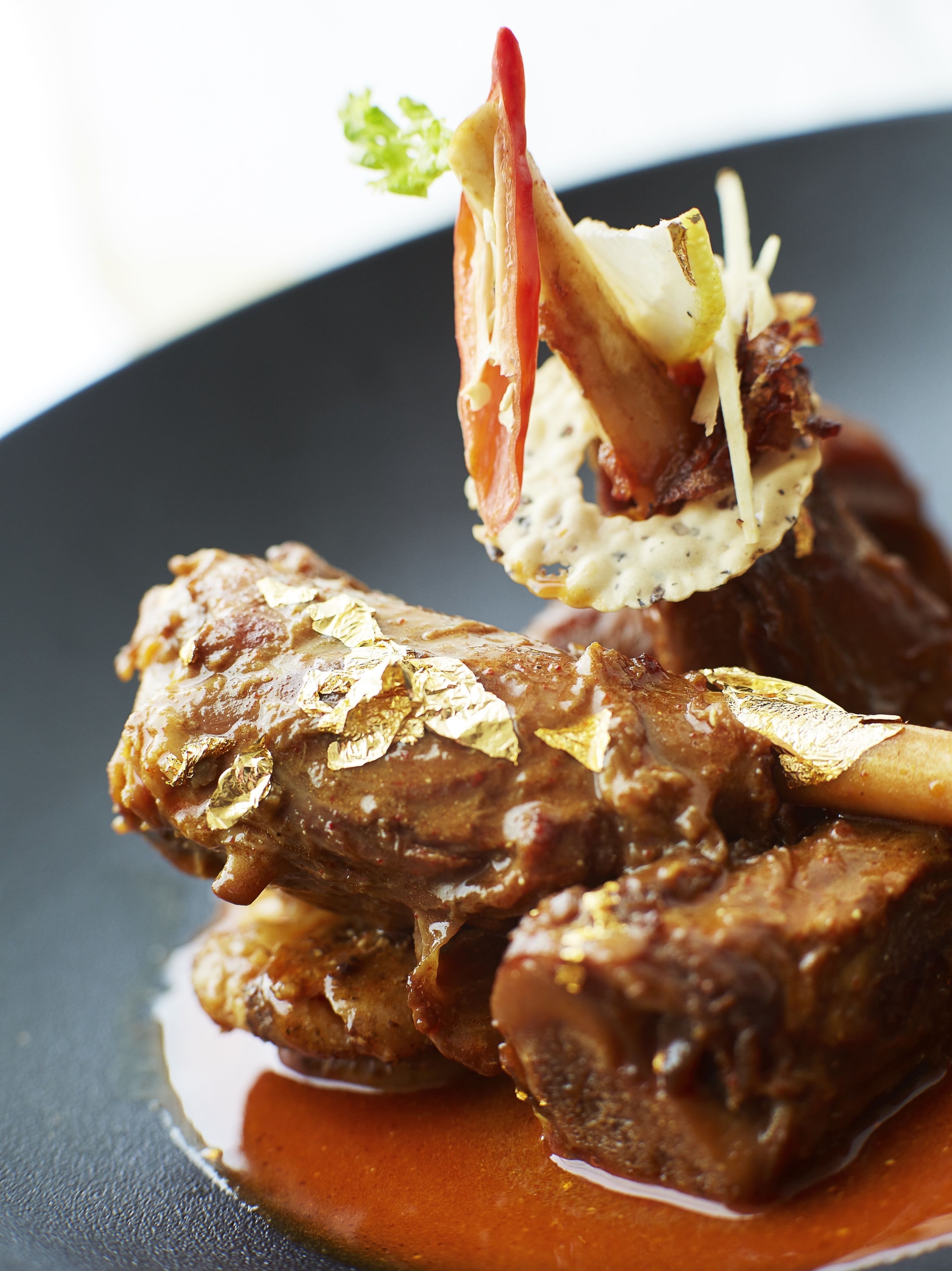 A dish with meat, vegetables, and a garnish on a plate.