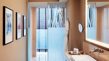 A modern bathroom with a large mirror, a white sink, and a glass shower enclosure.