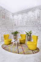 Una habitación con tres sillas amarillas, una mesita blanca y plantas en macetas.