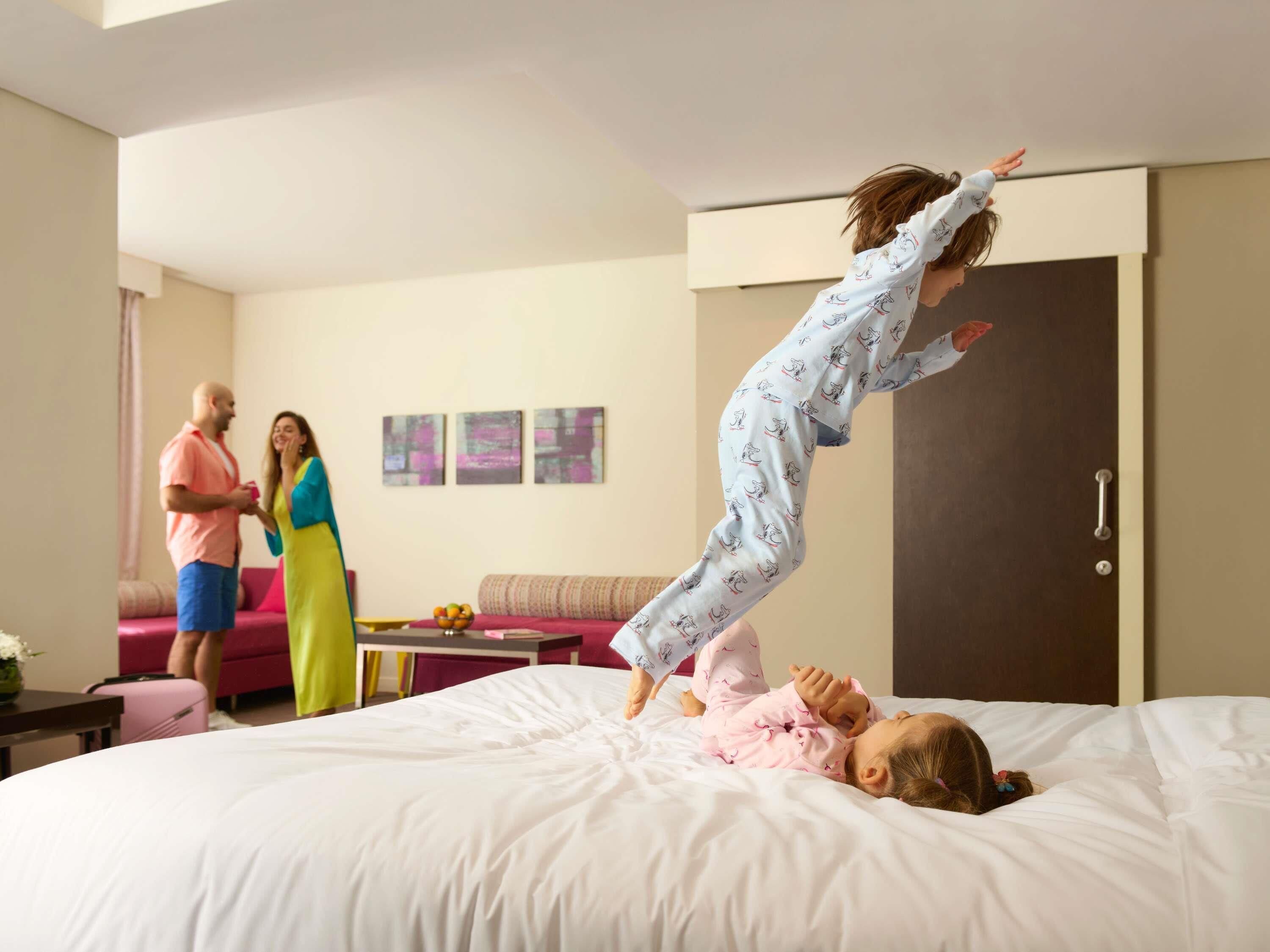 Un dormitorio con una cama, un sofá, una puerta y una pared con tres cuadros enmarcados.