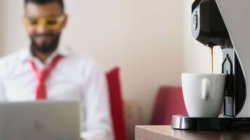 A person using a laptop with a coffee machine in the foreground.