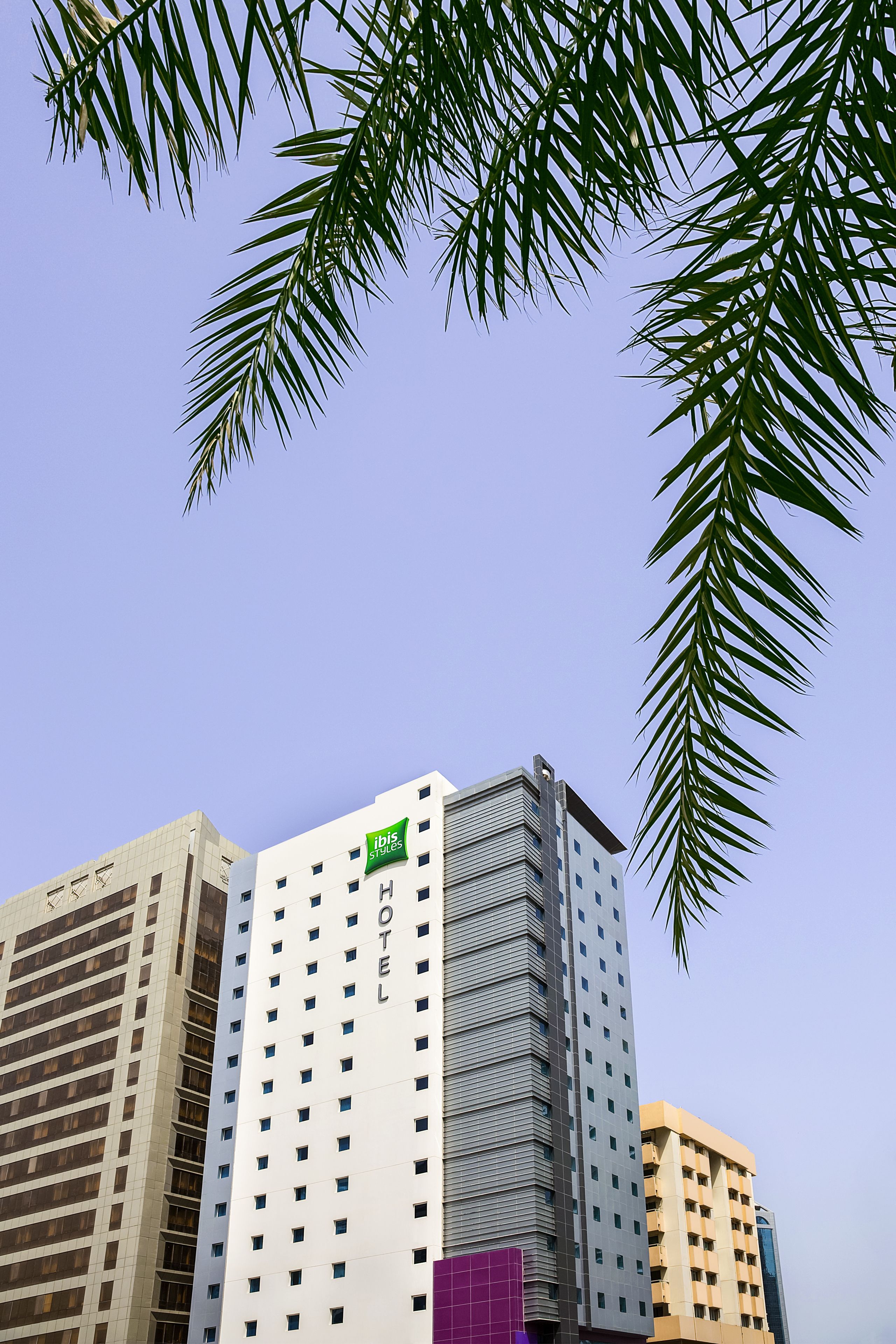 A hotel with a modern design, featuring a prominent "Ibis" logo on the facade.