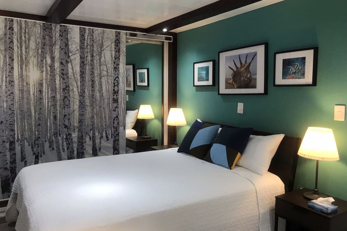 A hotel room with a large bed, two bedside lamps, a nightstand, and a wall with framed pictures.