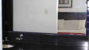 Un baño con espejo, lavamanos e inodoro. Hay un cuadro en la pared.