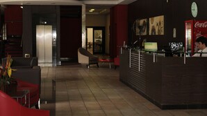 A hotel lobby with a reception desk, seating area, and a Coca-Cola refrigerator. - Hotel Dom Henrique (Timoteo)