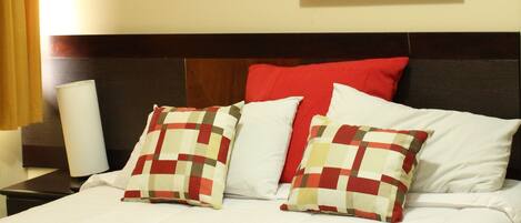 A hotel room with a bed, a framed picture on the wall, and an air conditioner above the bed.