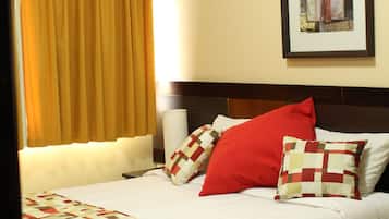 Quarto de hotel com cama, janela com cortinas, ar condicionado fixado na parede e quadro emoldurado.