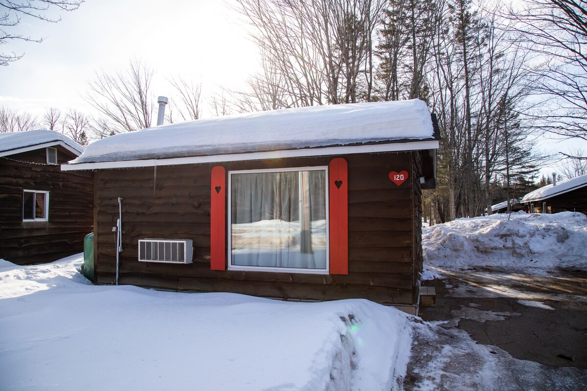 A small wooden cabin with a window, a door, and a chimney.