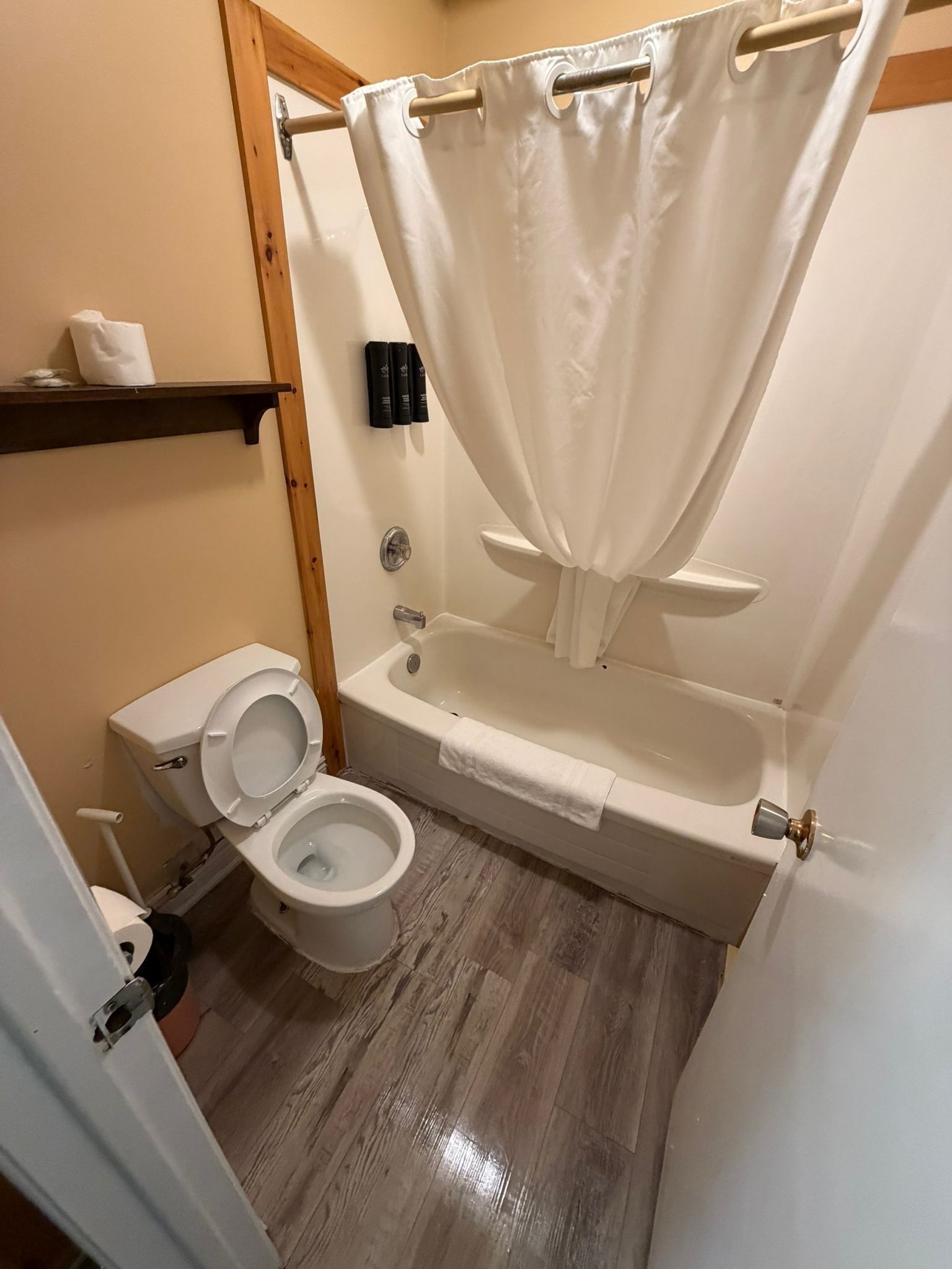 Une salle de bain équipée de toilettes, d’une baignoire et d’un rideau de douche.