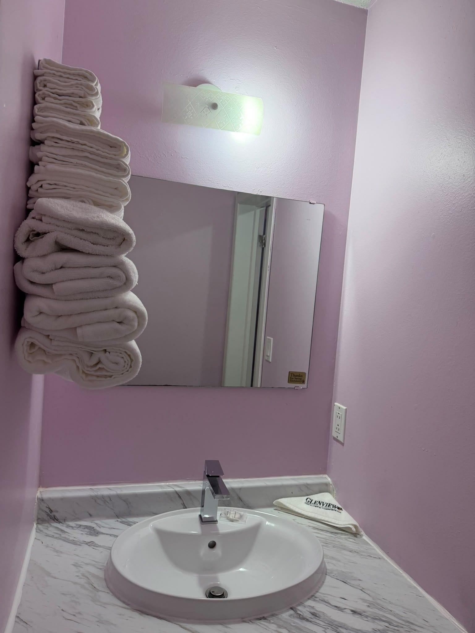 A bathroom with a sink, mirror, and a towel rack.