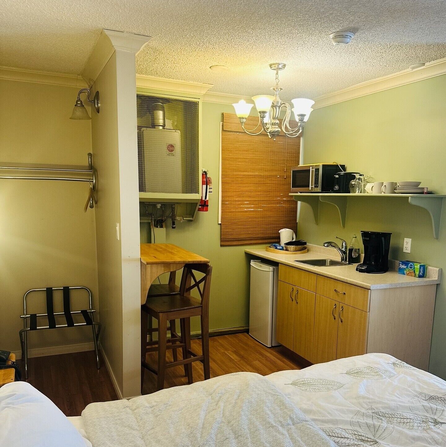 Una cocina compacta con microondas, cafetera y un refrigerador pequeño.