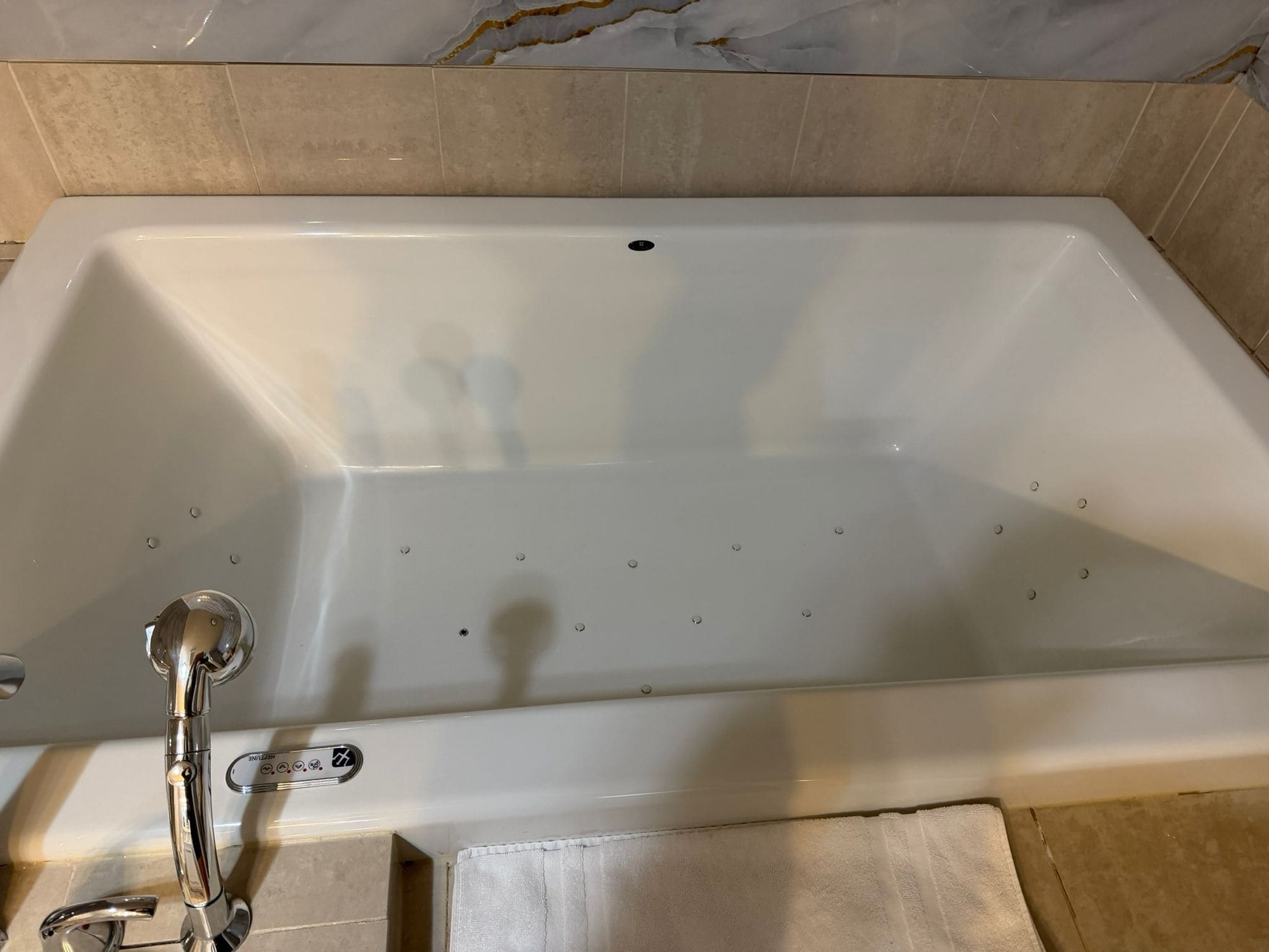 A bathtub with a chrome faucet and a control panel.