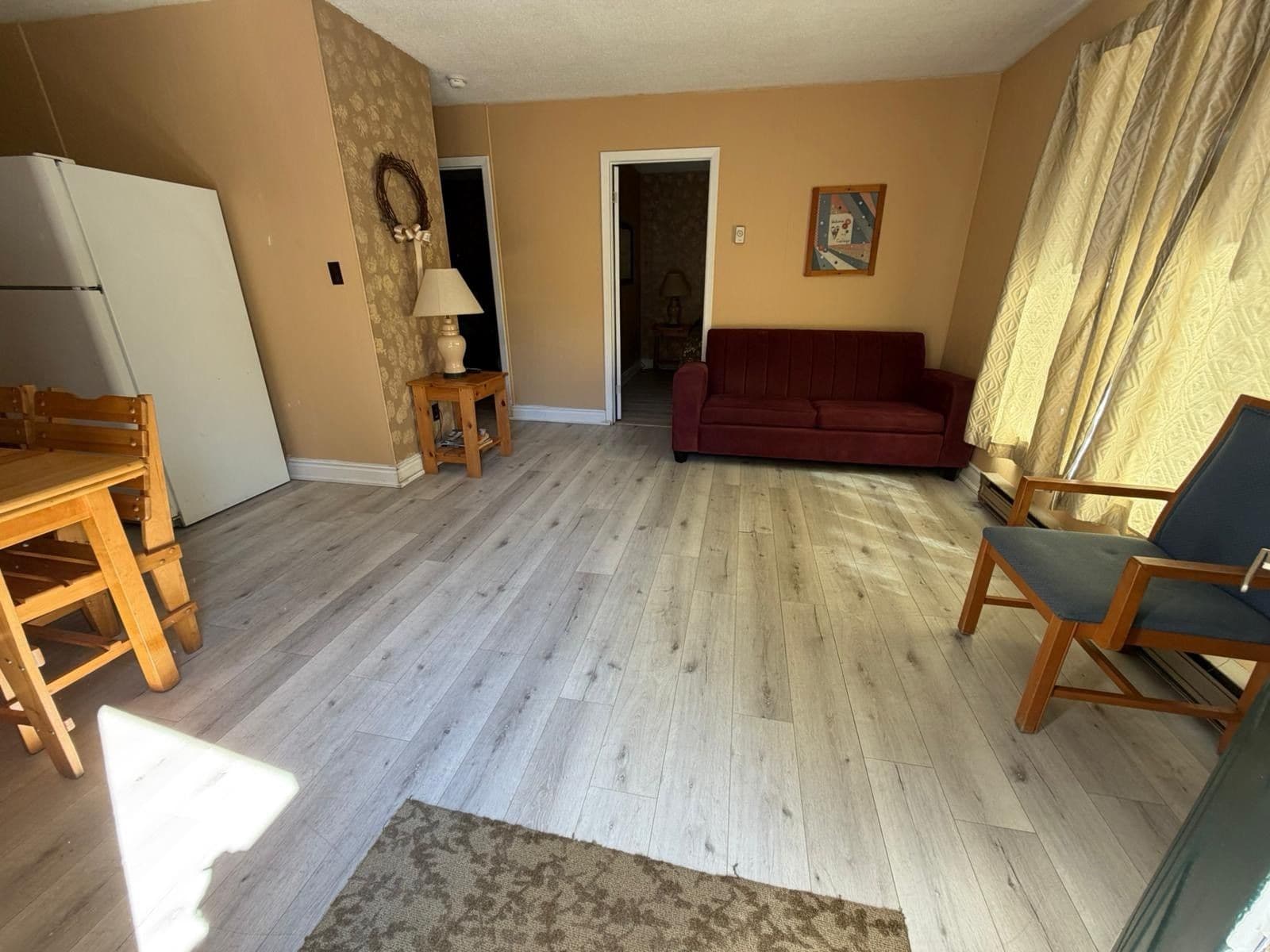 Un soggiorno con pavimento in legno, un divano rosso, un tavolo in legno e una sedia.