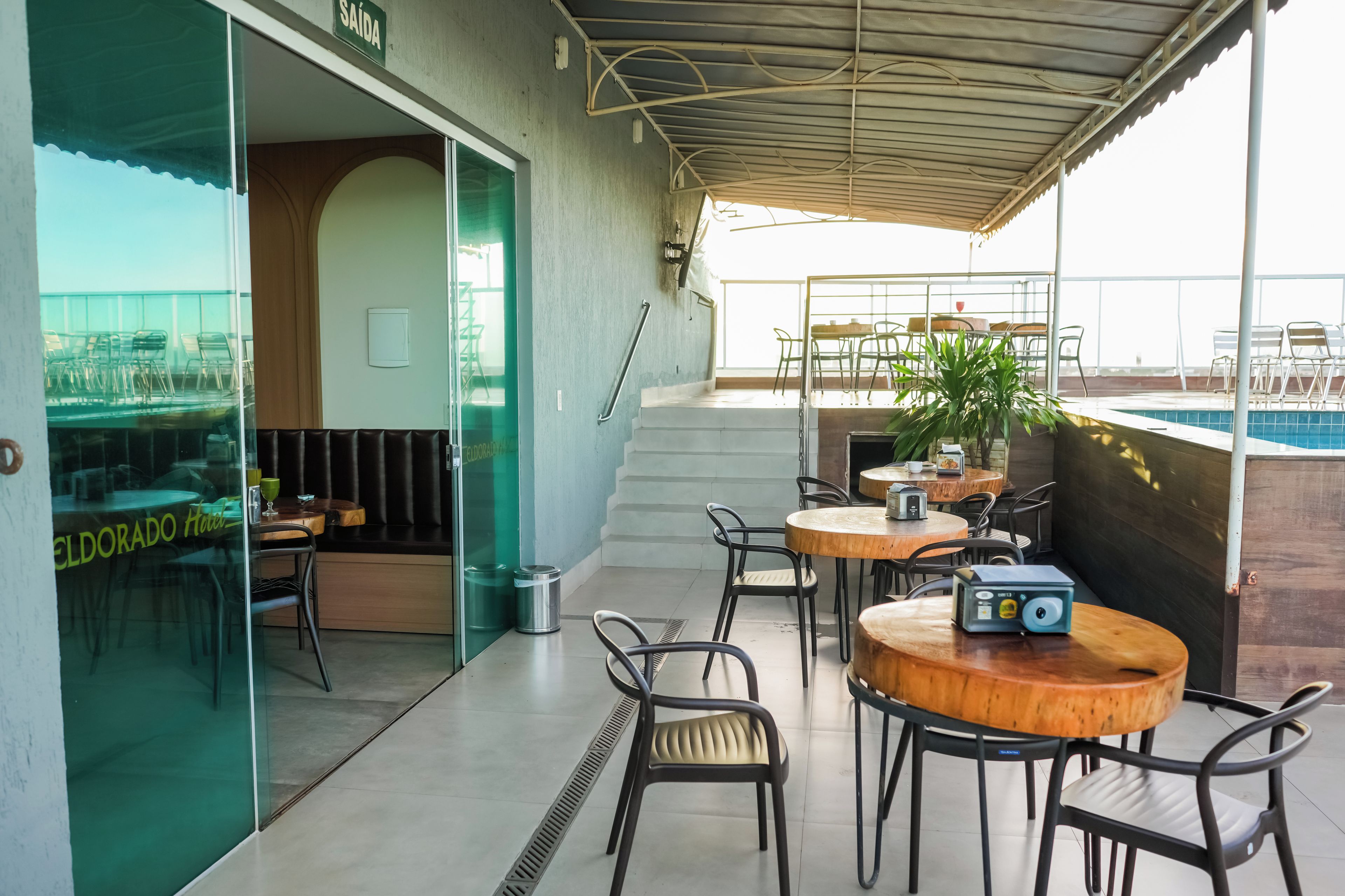 An outdoor seating area with tables and chairs, a pool, and a staircase leading to an upper level.