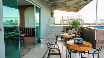 An outdoor seating area with tables and chairs, a pool, and a staircase leading to an upper level.