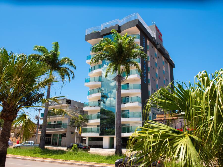 A modern hotel with multiple floors, balconies, and a clear blue sky.
