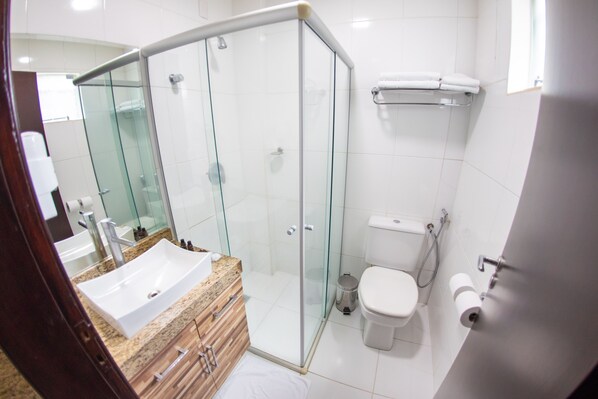 A modern bathroom with a glass shower enclosure, a sink with a marble countertop, a toilet, and a towel rack. - Hotel Eldorado Paracatu (Paracatu)