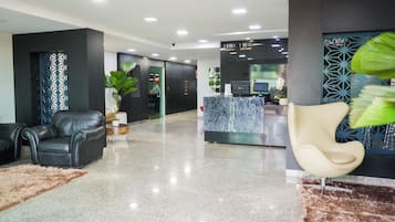 A modern lobby with a reception desk, seating area, and a decorative wall.