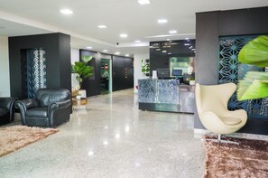 A modern lobby with a reception desk, seating area, and a decorative wall.
