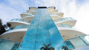 A modern building with a glass facade and multiple balconies.
